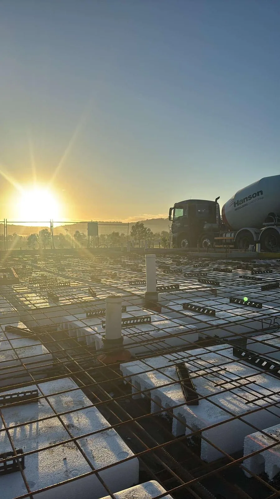Concrete truck beside mesh at sunrise